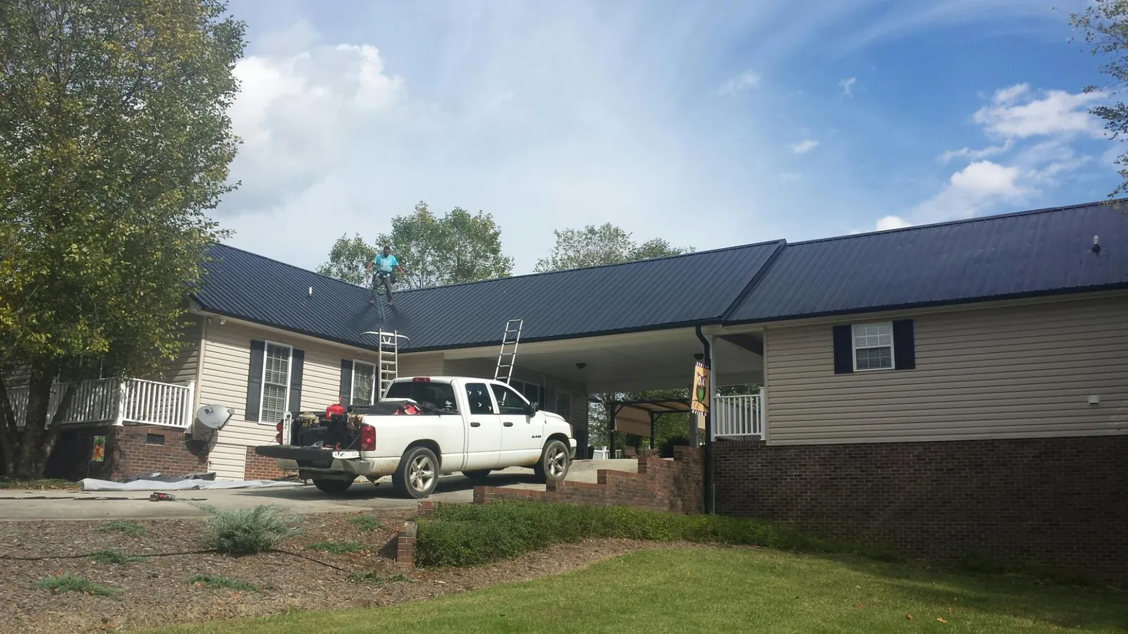 Black metal roof over a home and attached breezeway with ladders set in Lynchburg